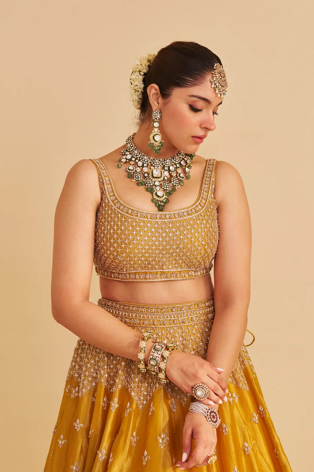 Woman in a traditional yellow lehenga with jewelry on a beige background