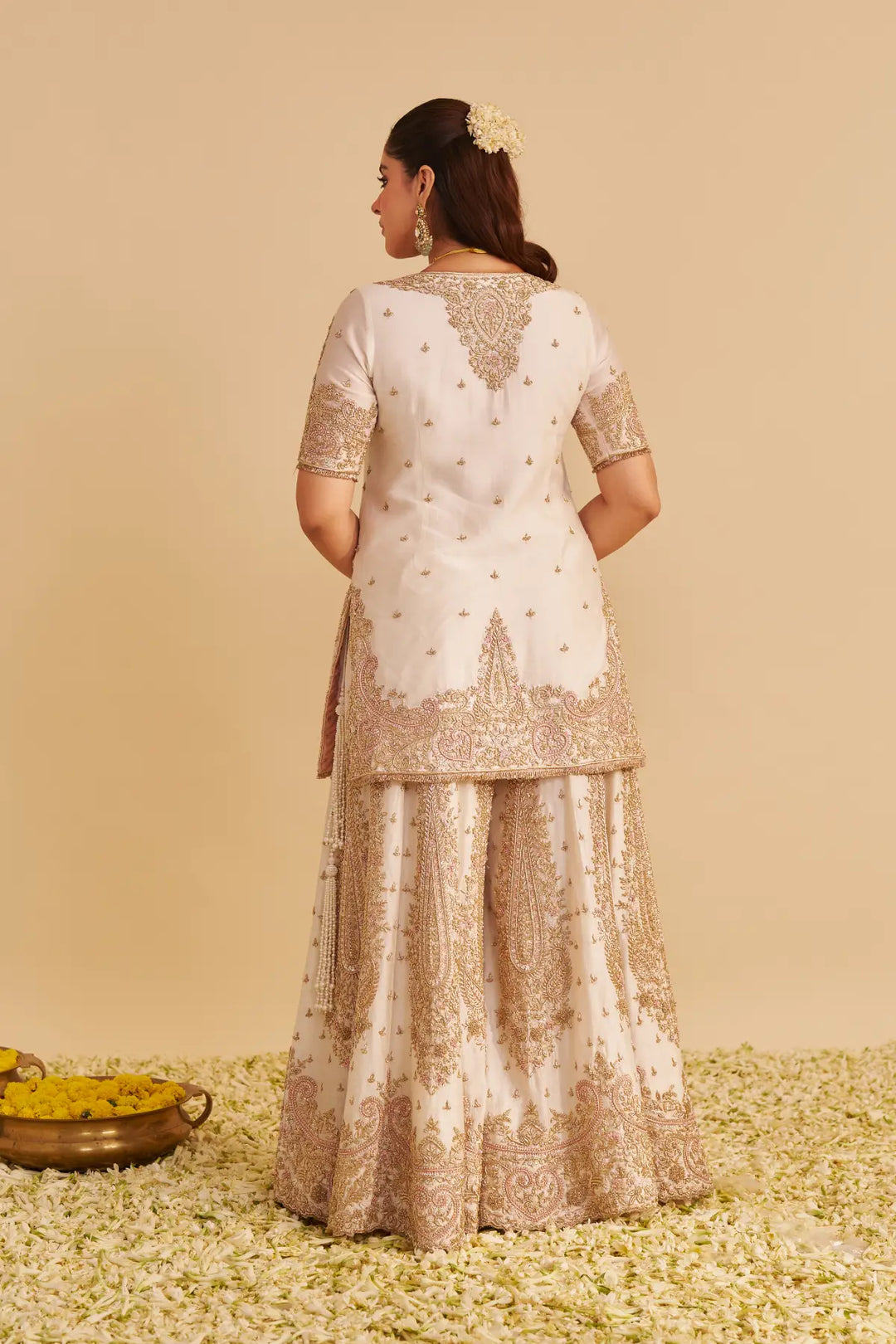 Woman wearing a traditional outfit with intricate designs on a beige background