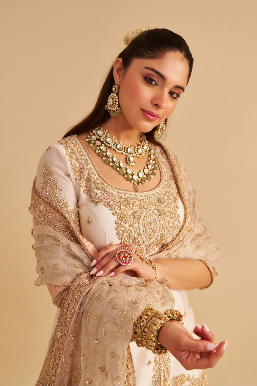 Woman in traditional embroidered Sharara with jewellery on a beige background