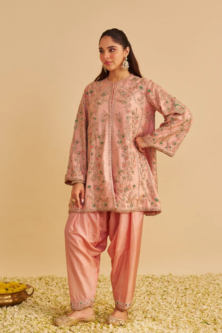 Woman wearing a pink traditional outfit with floral patterns on a beige background