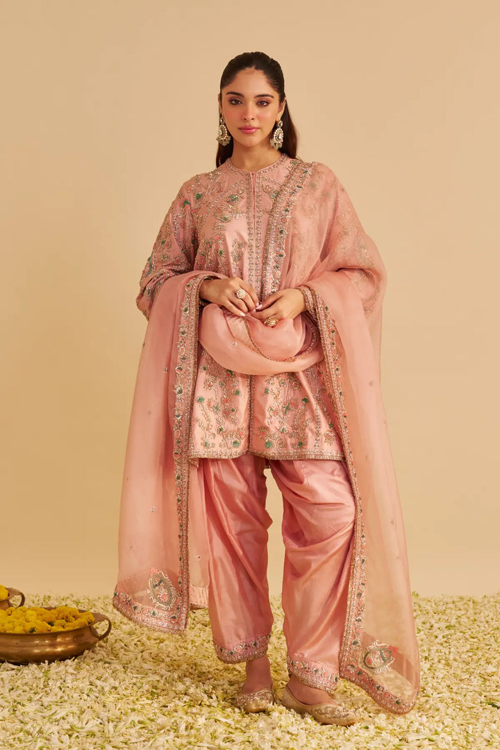 Woman in a traditional pink outfit with floral patterns on a beige background