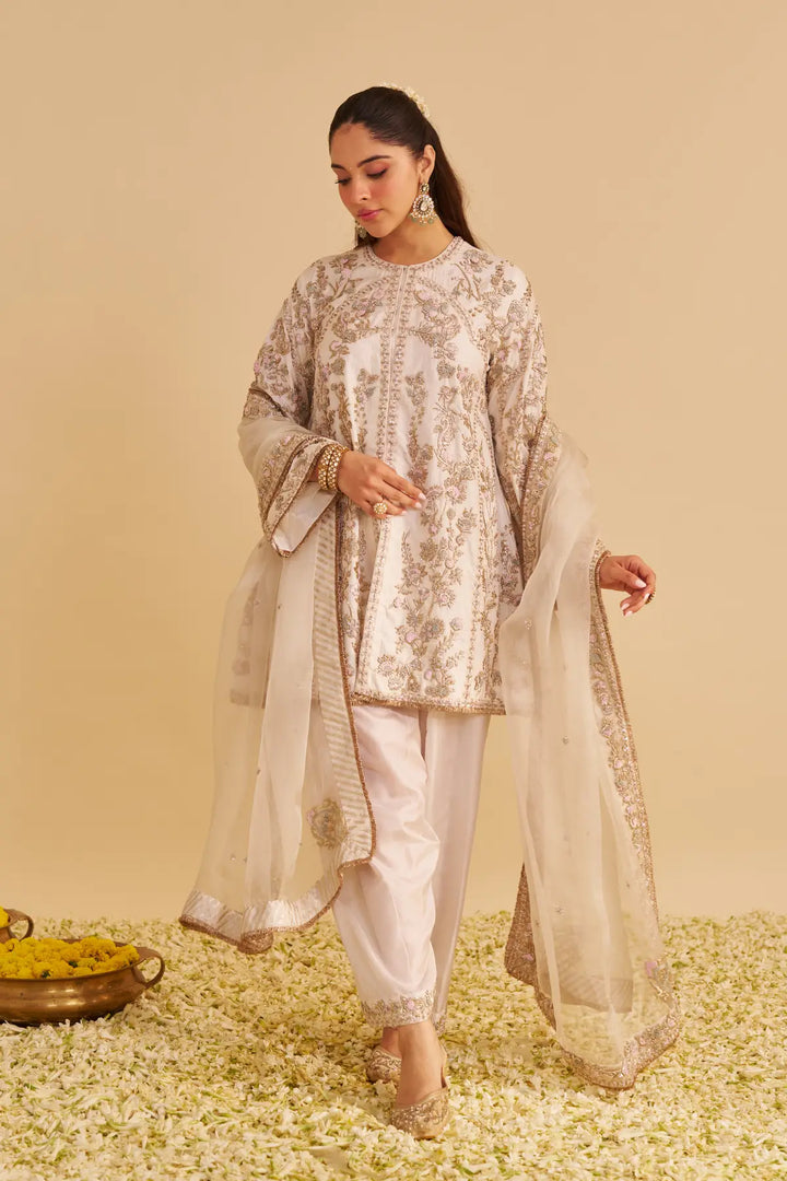 Woman in traditional outfit with floral patterns on a beige background