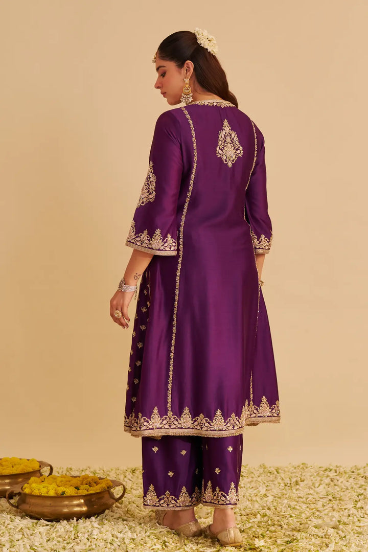 Purple traditional outfit with gold embroidery on a beige background