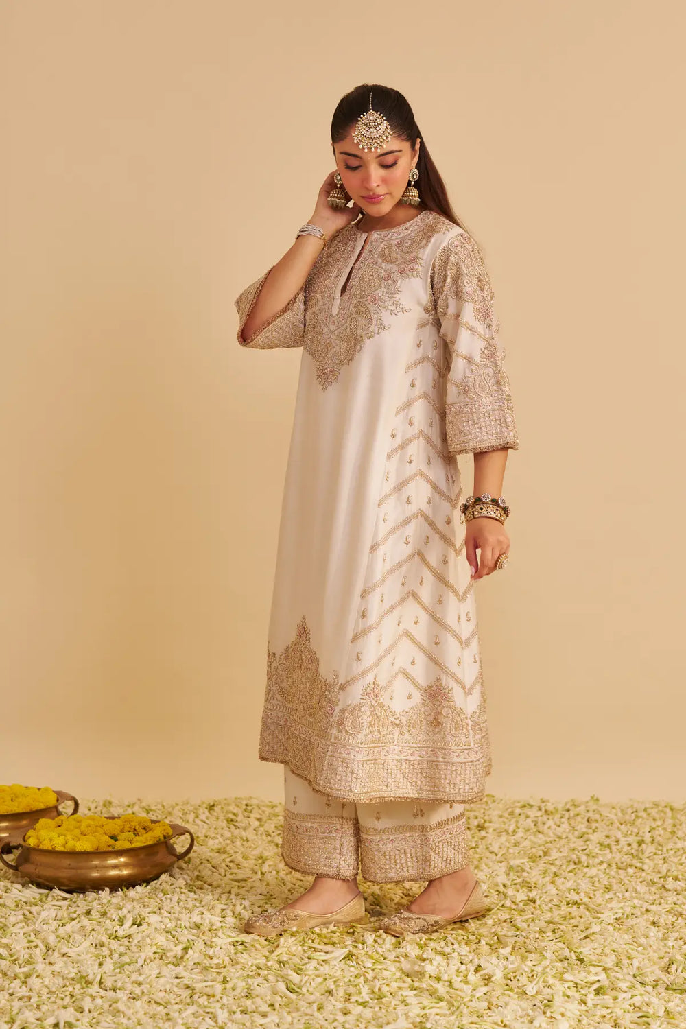 Woman wearing an embroidered traditional kurta on a beige background