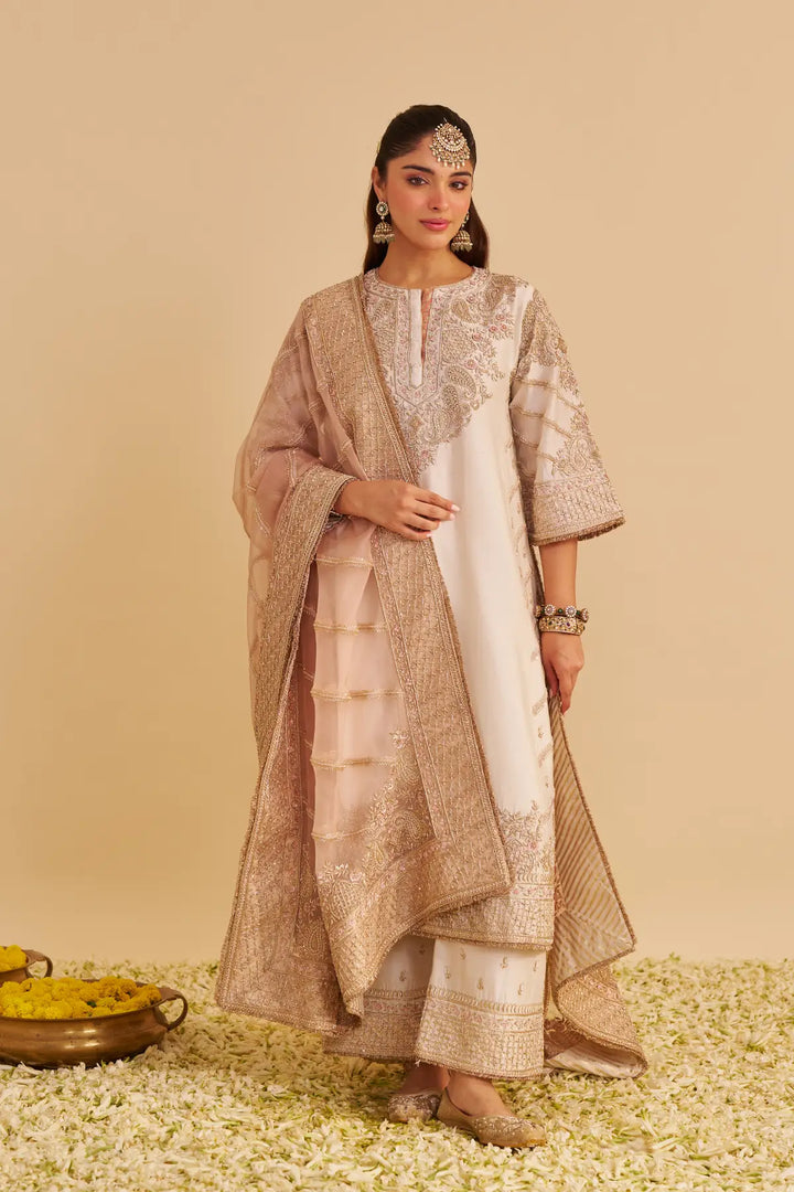 Woman in traditional kurta with floral decorations on a beige background