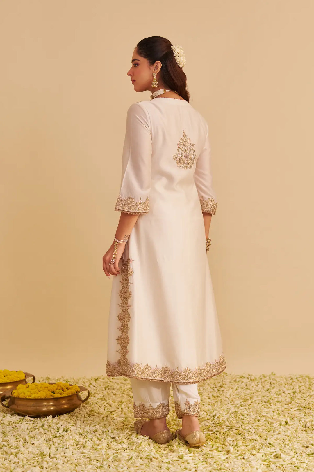 Woman wearing a white embroidered traditional outfit on a beige background