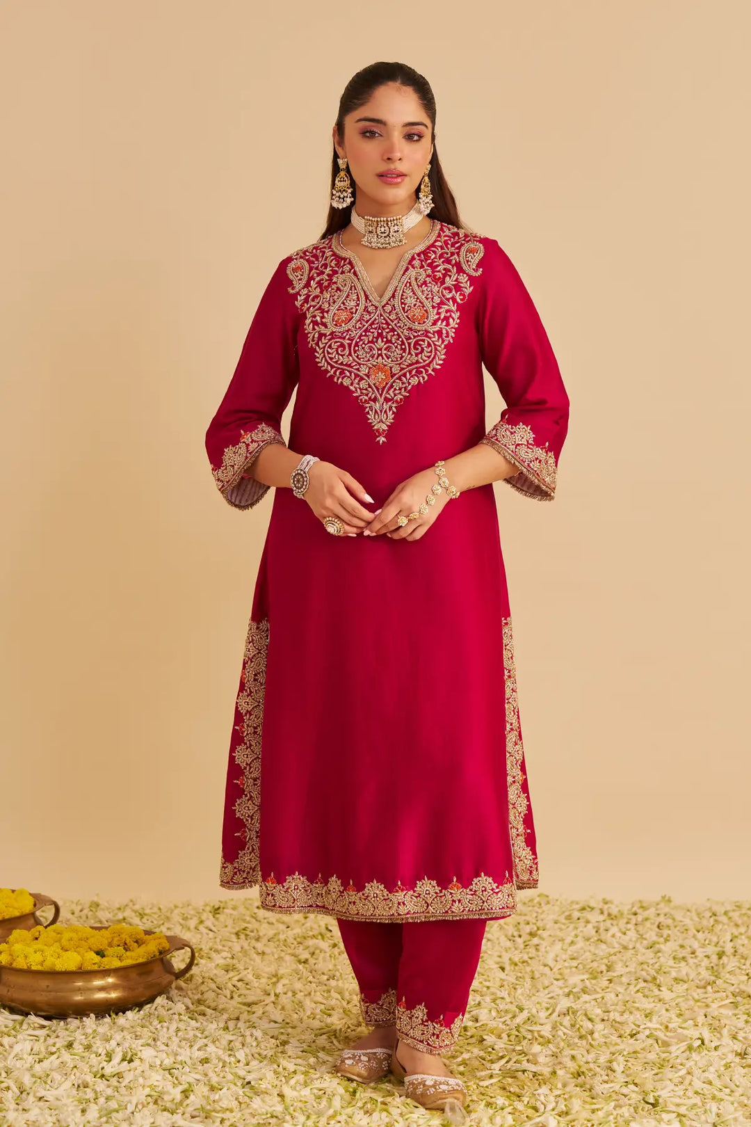 Woman wearing a red embroidered traditional outfit on a beige background