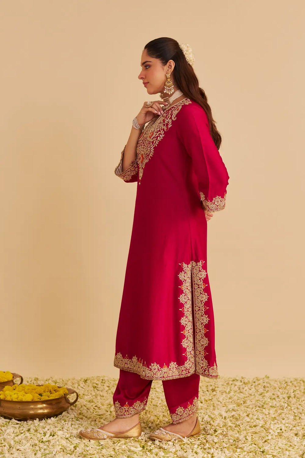 Woman in a red traditional outfit with gold embroidery on a beige background