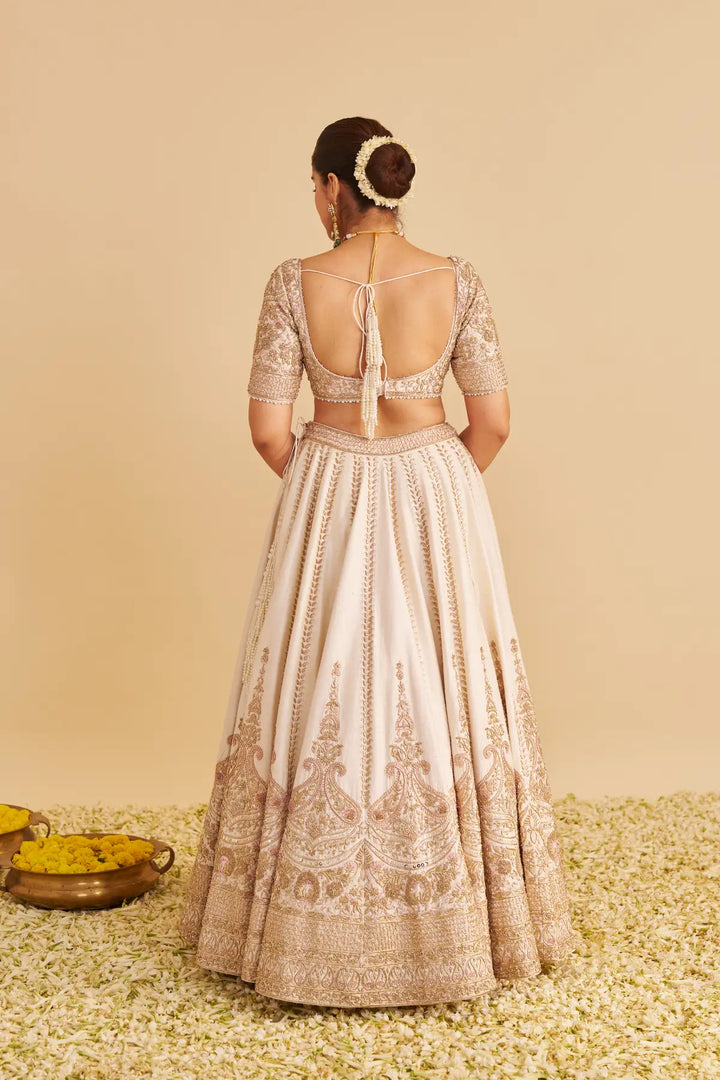 Woman wearing a traditional outfit with intricate patterns on a beige background