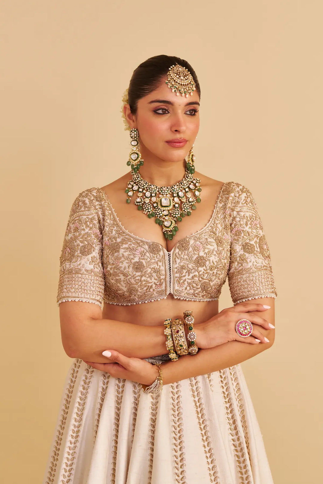 Woman in traditional Indian attire with jewelry on a beige background