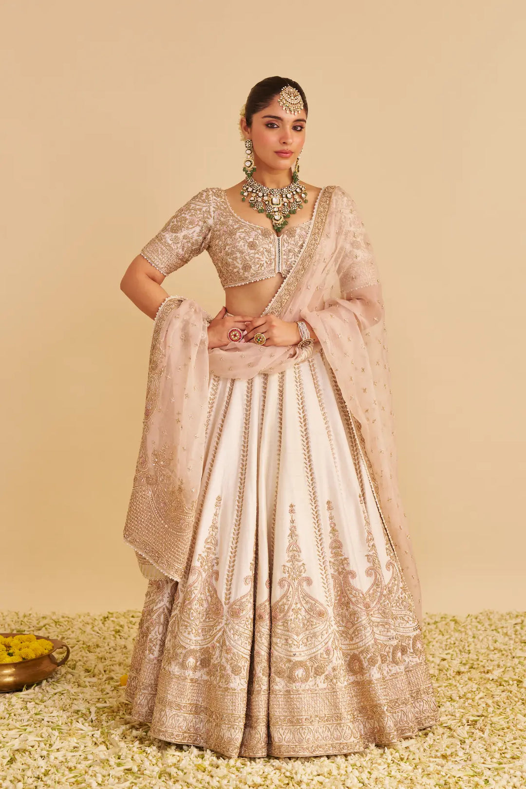 Woman in traditional beige and pink lehenga with jewelry on a beige background