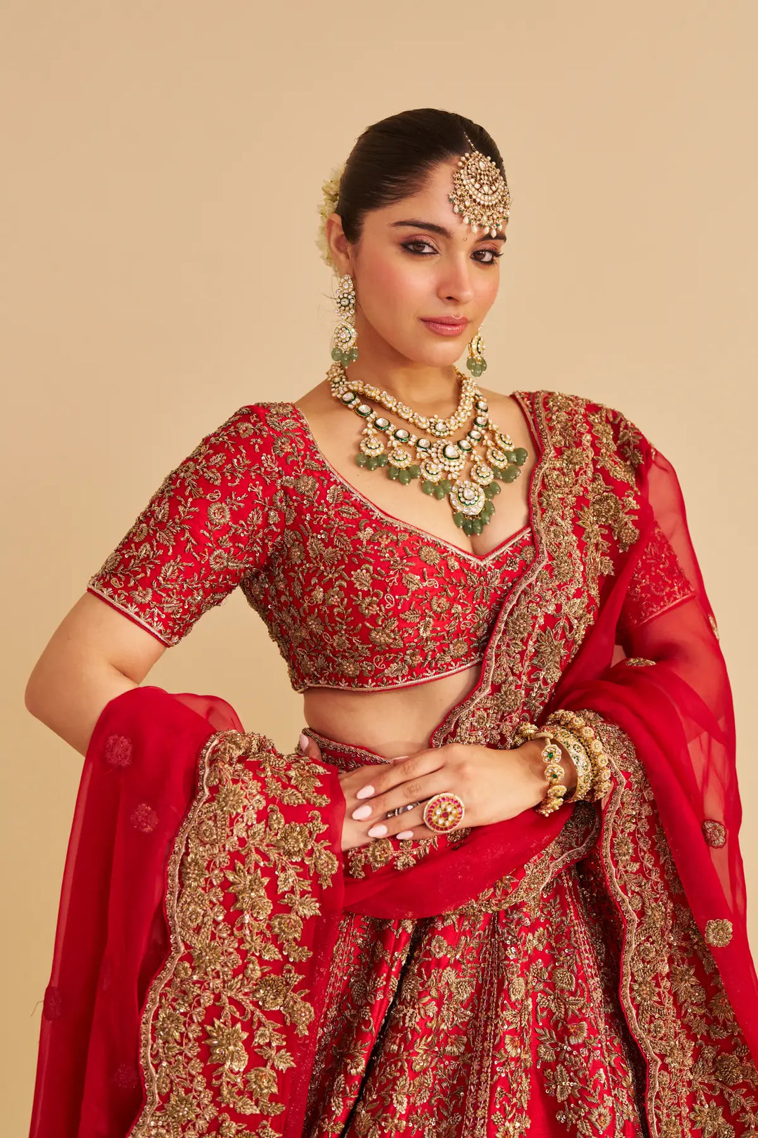 Woman in a red traditional outfit with gold embroidery on a beige background