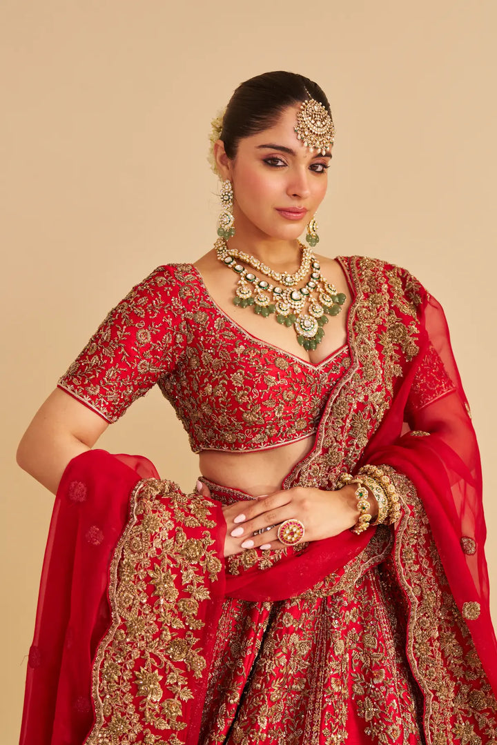 Woman in a red traditional outfit with gold embroidery on a beige background