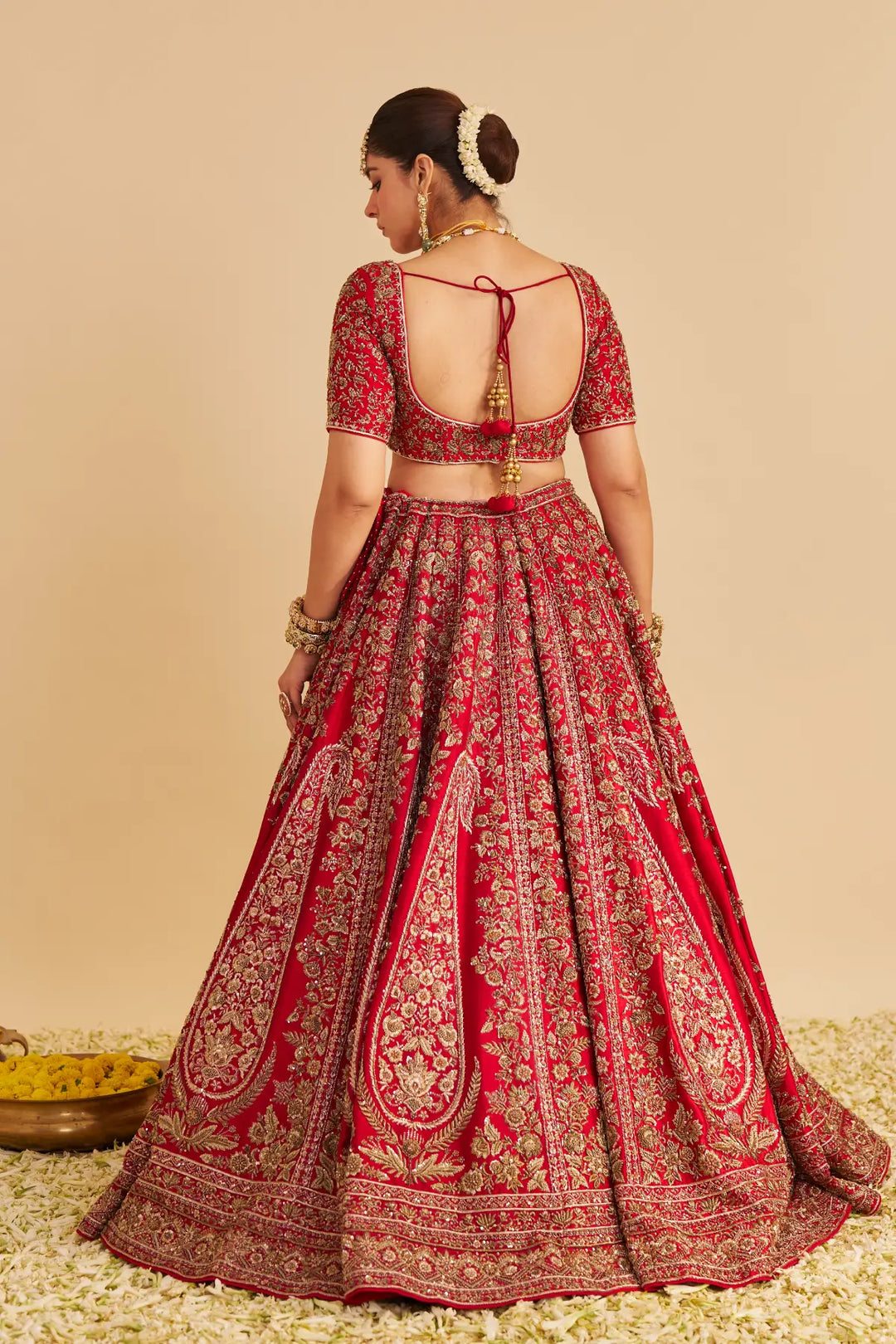 Red and gold traditional outfit with intricate patterns on a beige background