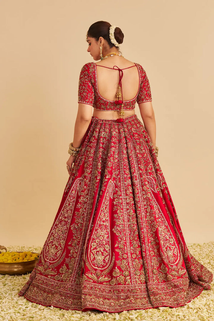 Red and gold traditional outfit with intricate patterns on a beige background