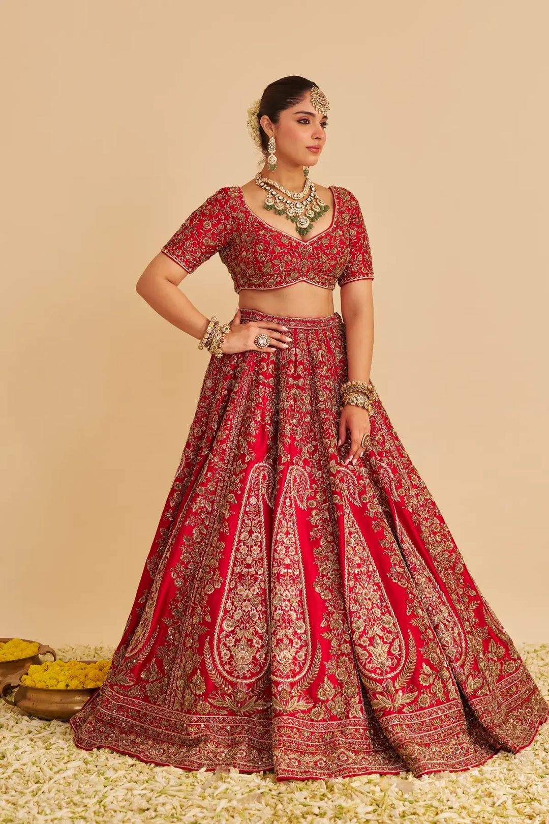 Woman wearing a red embroidered traditional outfit with jewelry on a beige background