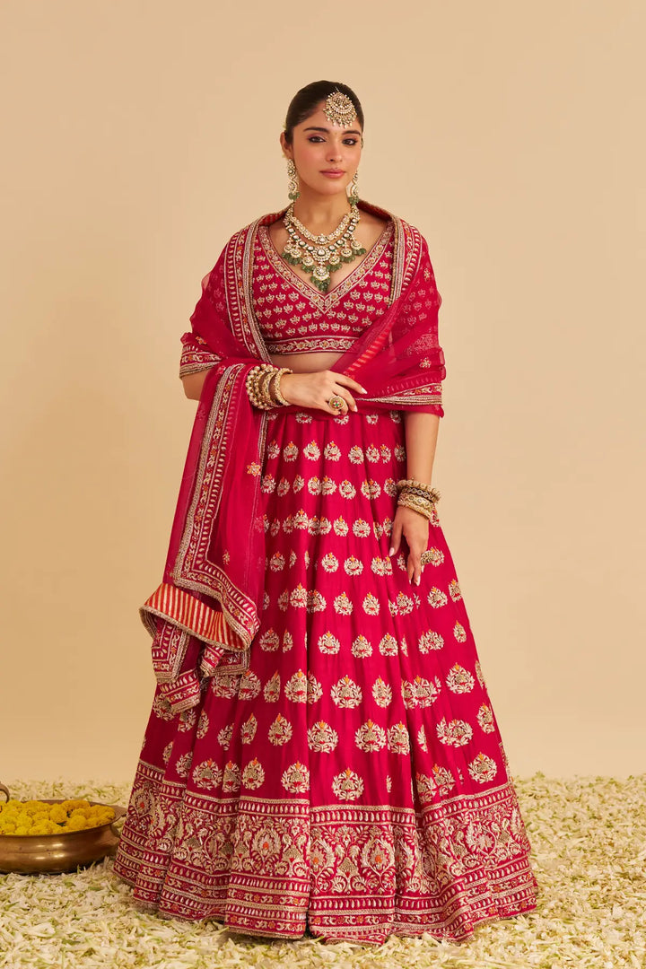 Woman in a traditional pink and gold embroidered lehenga on a beige background