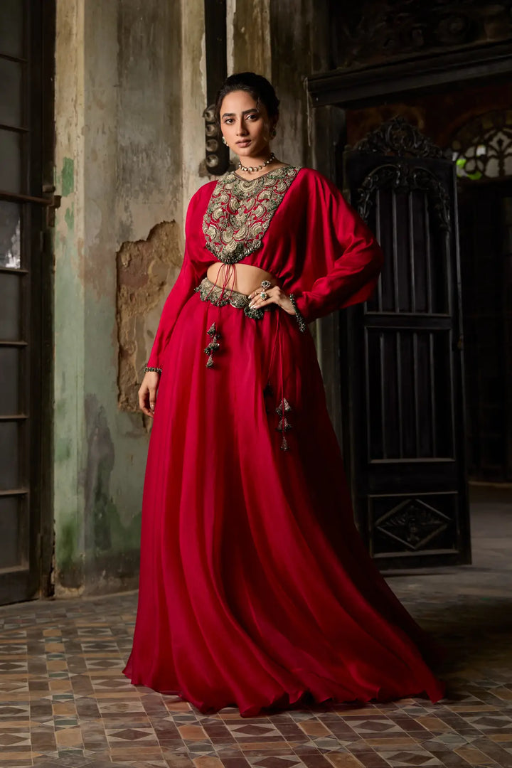 Woman in a red traditional Skirt standing in a dimly lit room.