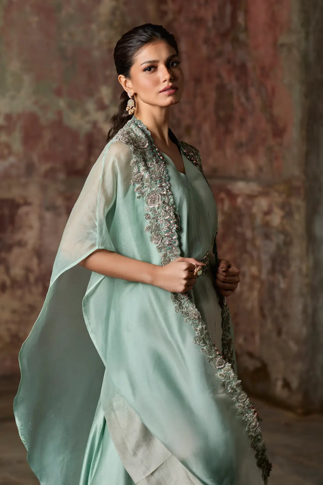 Woman wearing a light blue cape set with a textured background