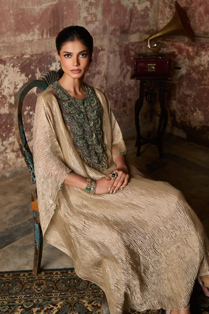 Woman in a beige and green traditional kaftan sitting on a chair with a vintage gramophone in the background.