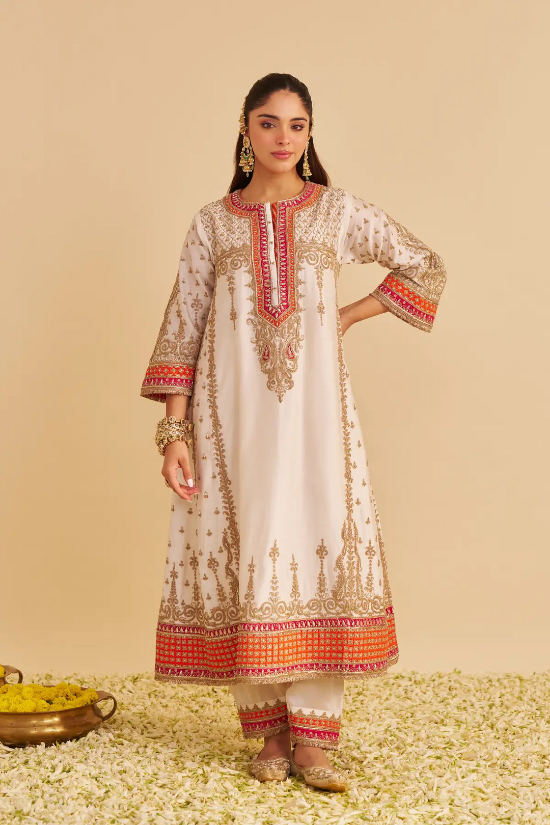 Woman wearing a traditional outfit with intricate patterns on a beige background