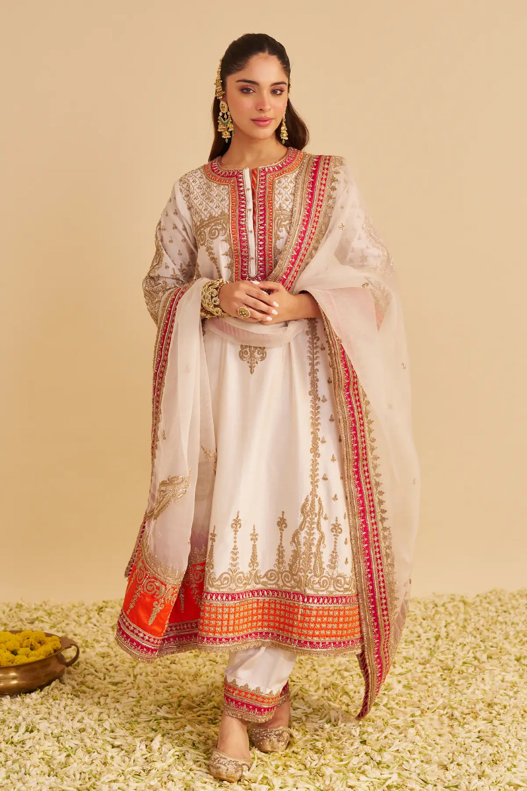 Woman wearing a traditional outfit with intricate designs on a beige background