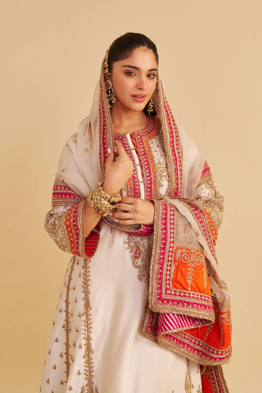Woman wearing a traditional outfit with intricate patterns on a beige background
