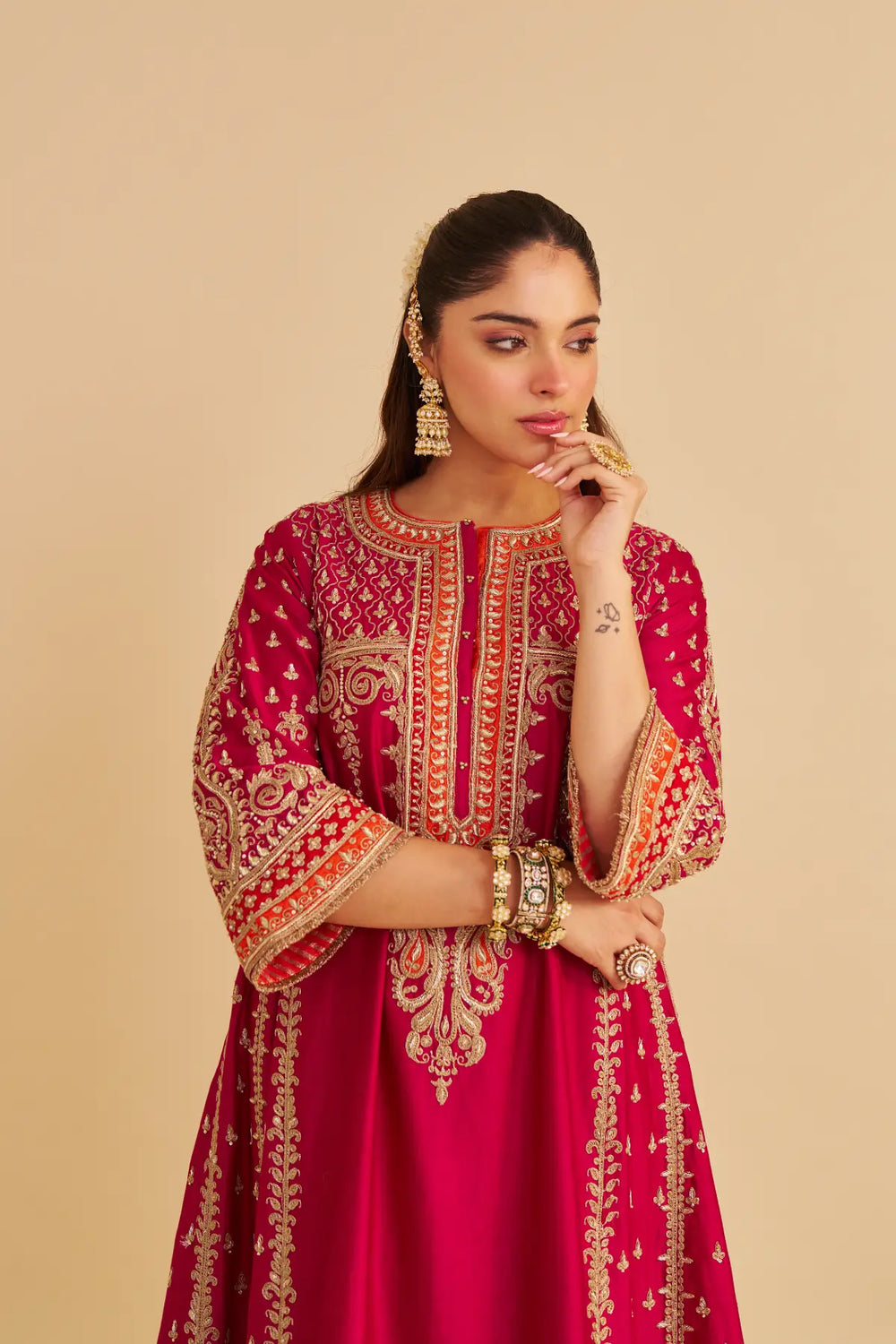 Woman wearing a red embroidered traditional Chauga on a beige background