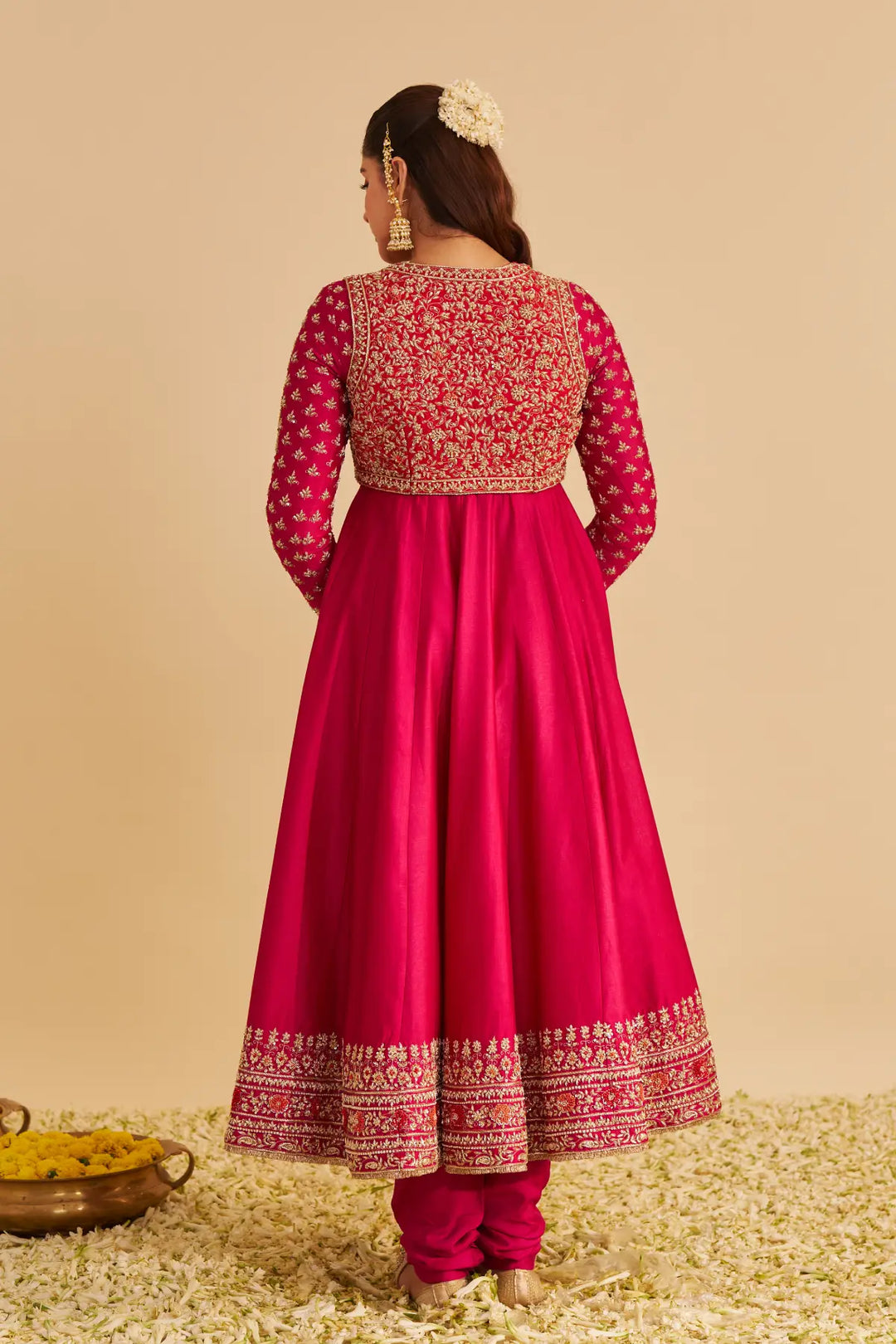 Woman wearing a red and gold traditional Anarkali with a beige background
