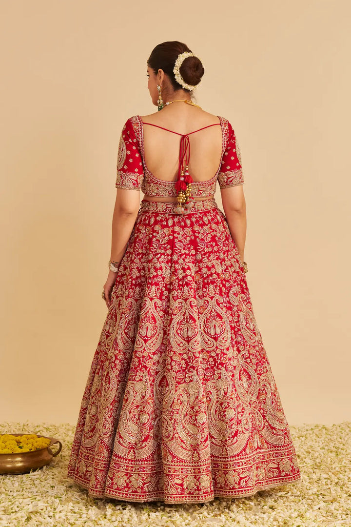 Red and gold embroidered traditional outfit on a beige background