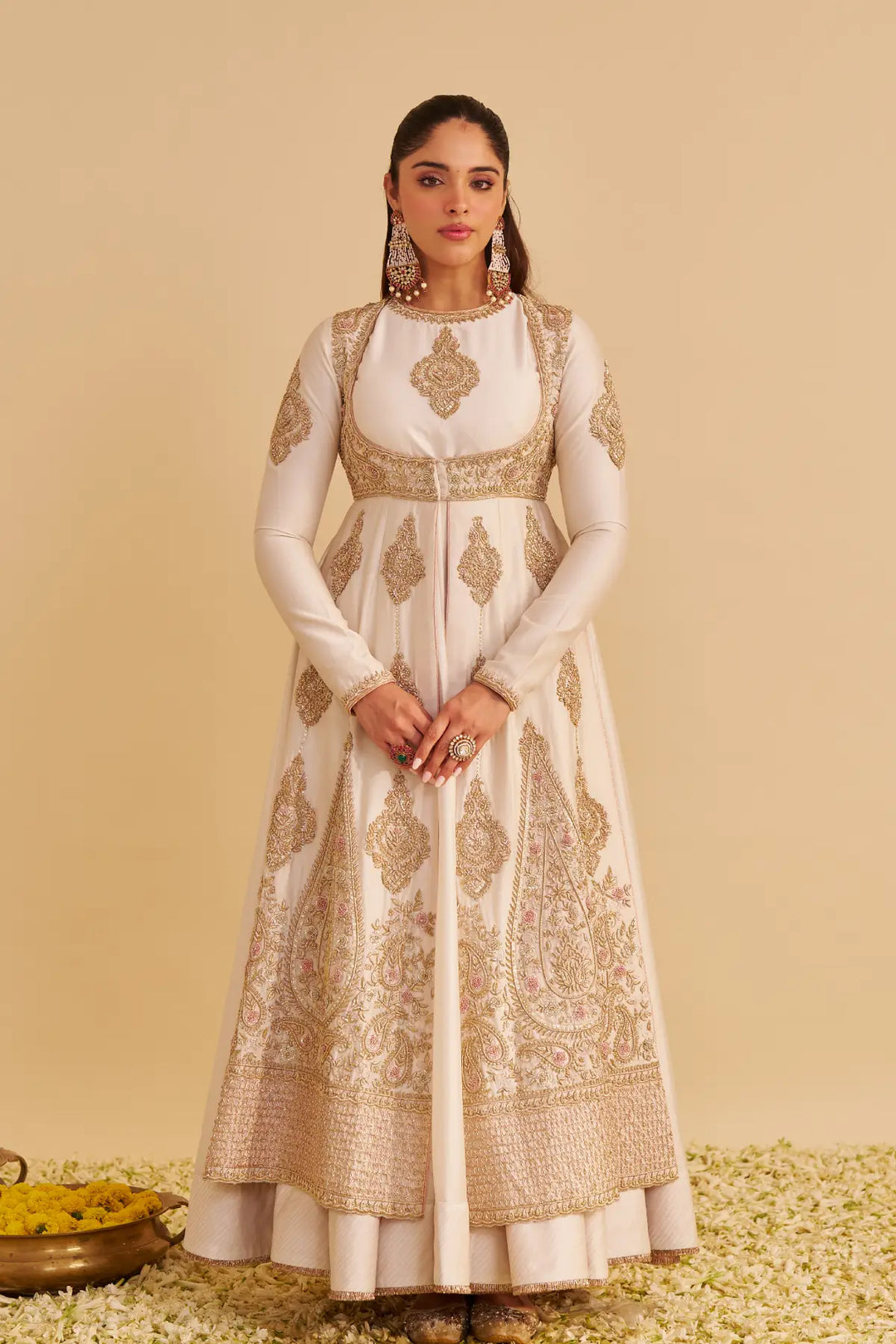 Woman wearing a traditional anarkali with intricate patterns on a beige background
