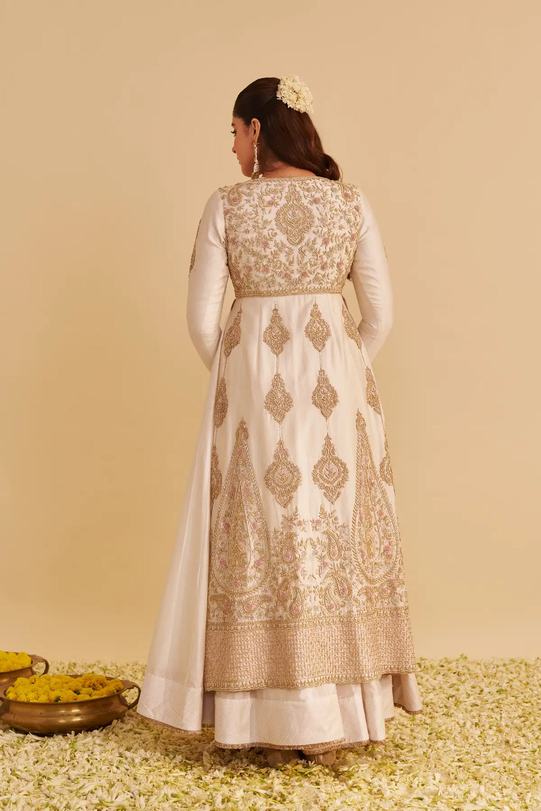 Woman wearing a traditional embroidered anarkali on a beige background