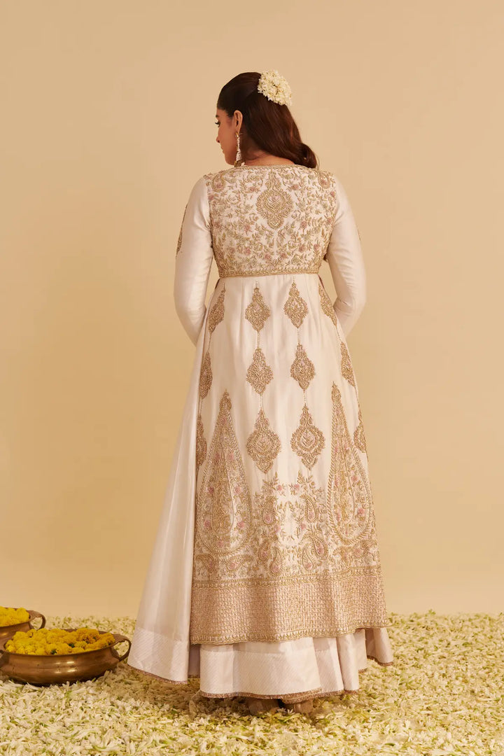 Woman wearing a traditional embroidered anarkali on a beige background