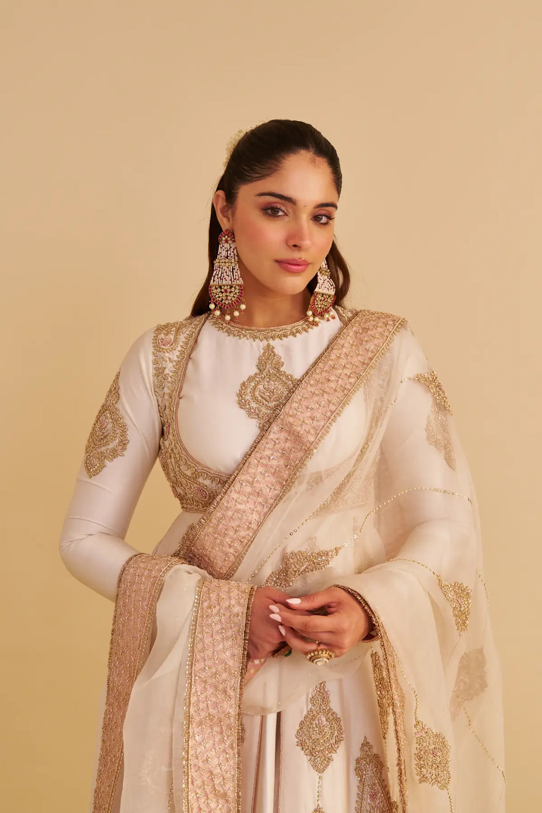 Woman wearing a traditional embroidered anarkali with a beige background