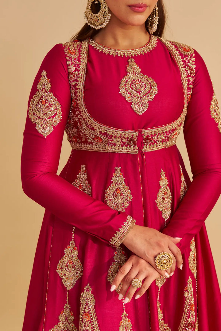 Red traditional anarkali with gold embroidery on a beige background